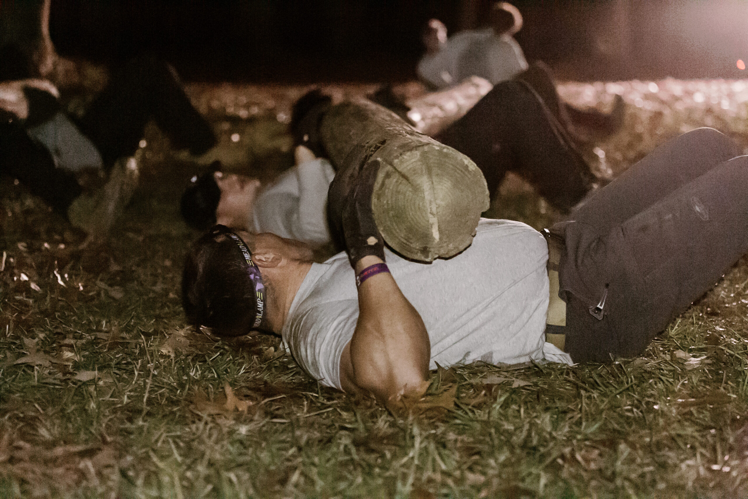 Men performing log presses on their backs during a night training session at a BASE 1520 camp